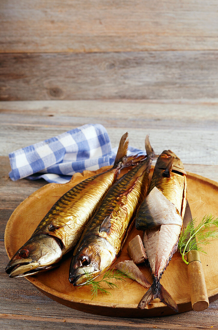 Smoked mackerel on a wooden board with a knife and napkin