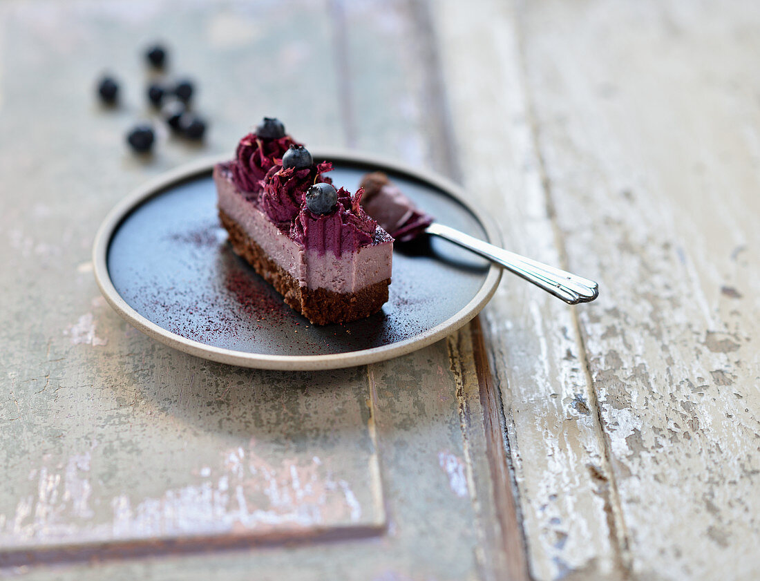 Veganer Himbeer-Blaubeer-Brownie mit frischen Heidelbeeren und getrockneten Blüten