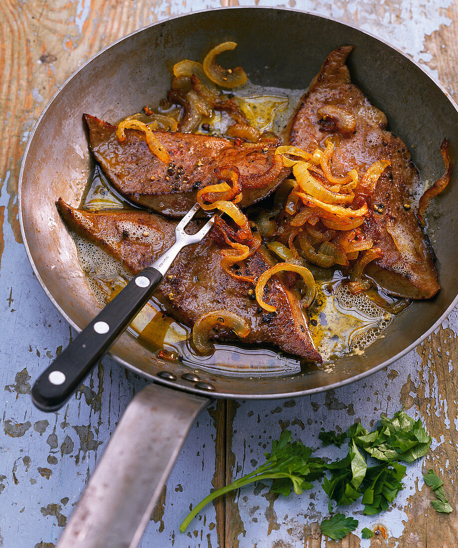 Calf's liver with onions in a frying pan