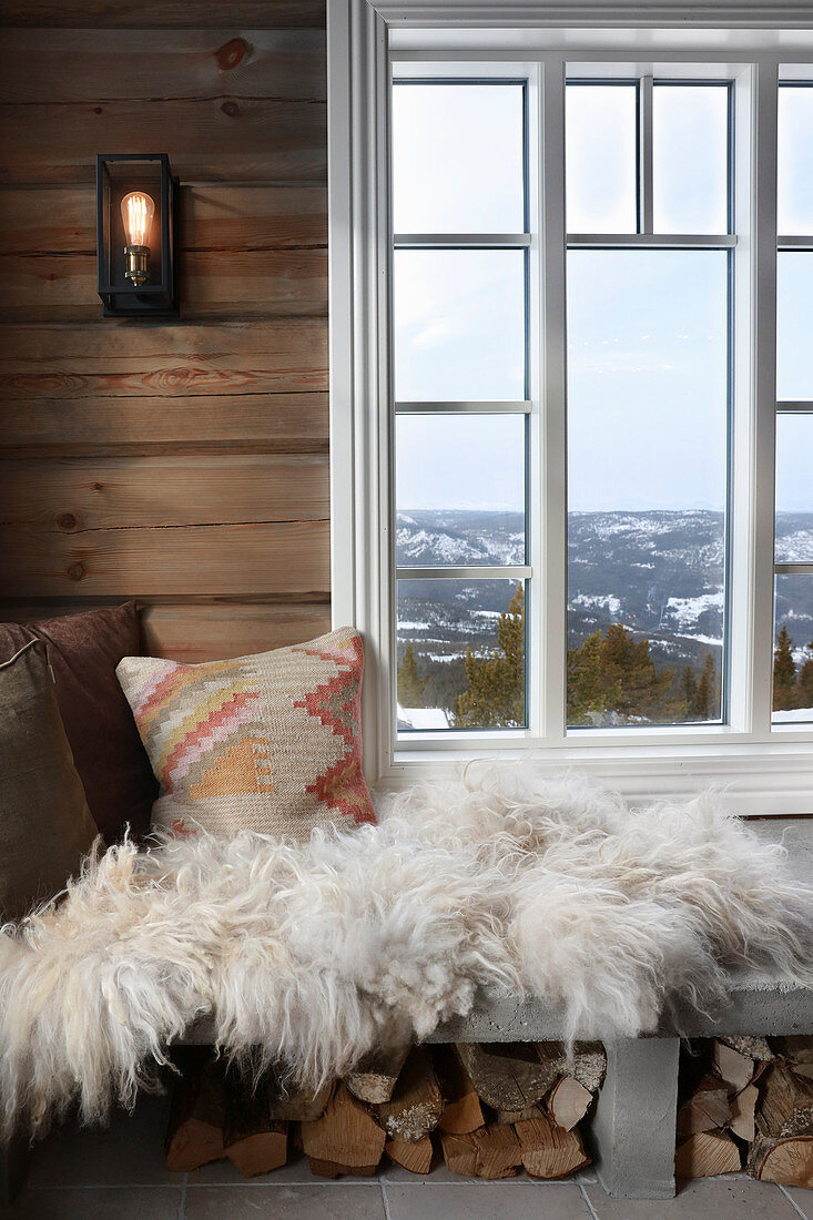 Sheepskin rug and cushions on masonry bench below window