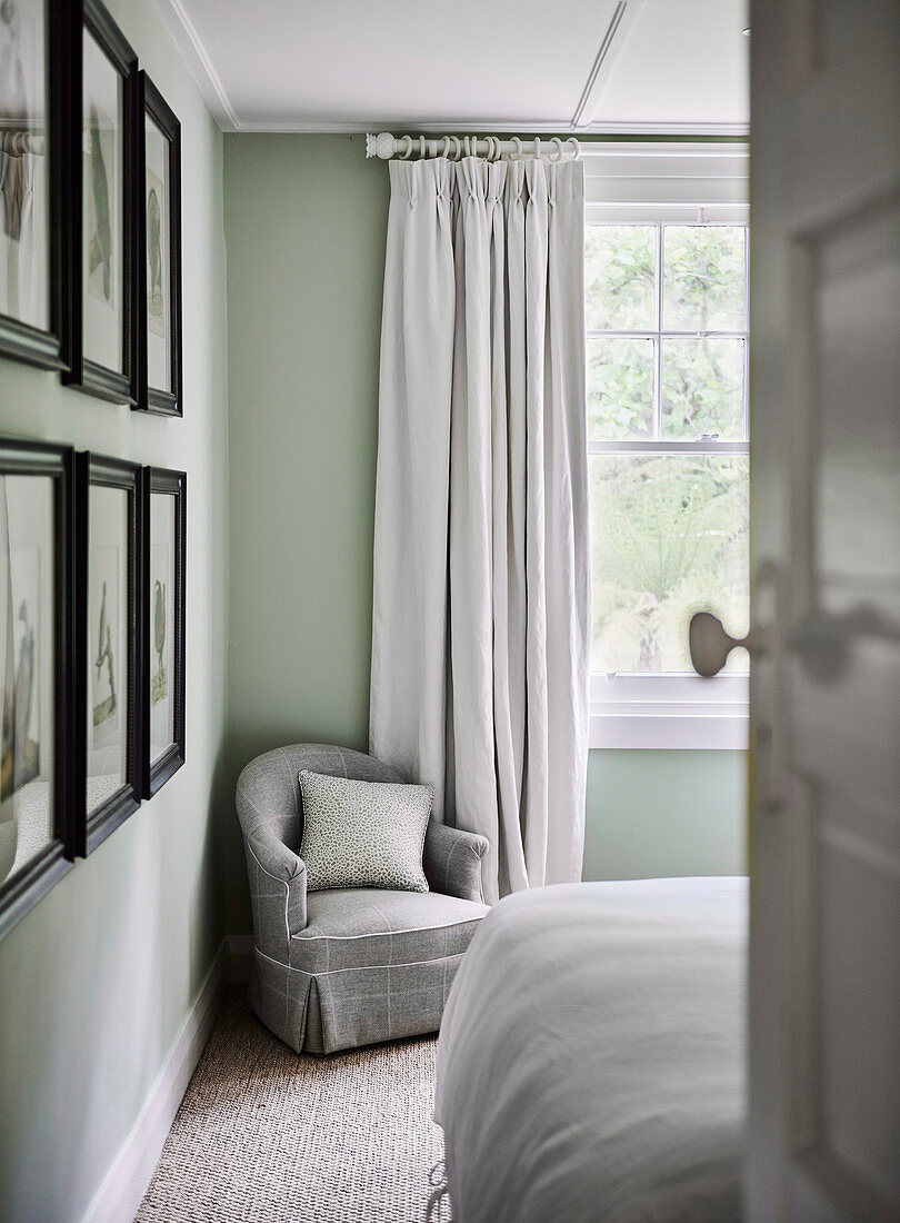 Gray upholstered armchair in corner of bedroom near window