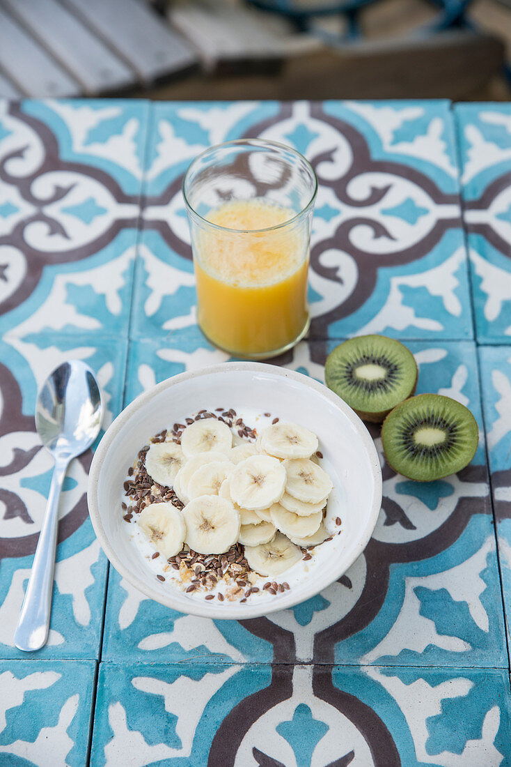 Müsli mit Leinsamen und Bananen, Orangensaft und Kiwi zum Frühstück
