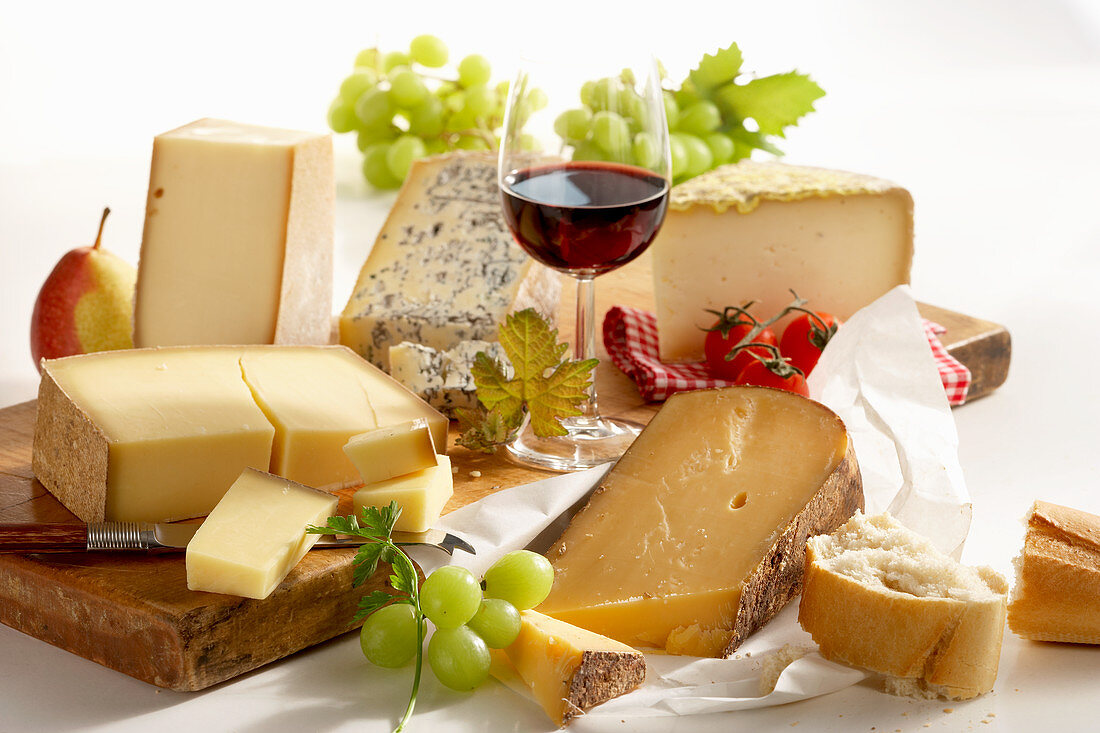 A still life of french cheeses with red wine and grapes