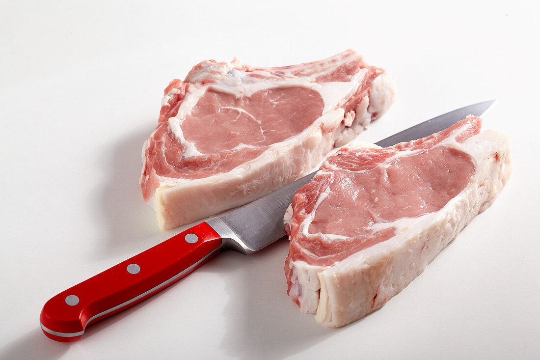 Two raw veal cutlets with a knife