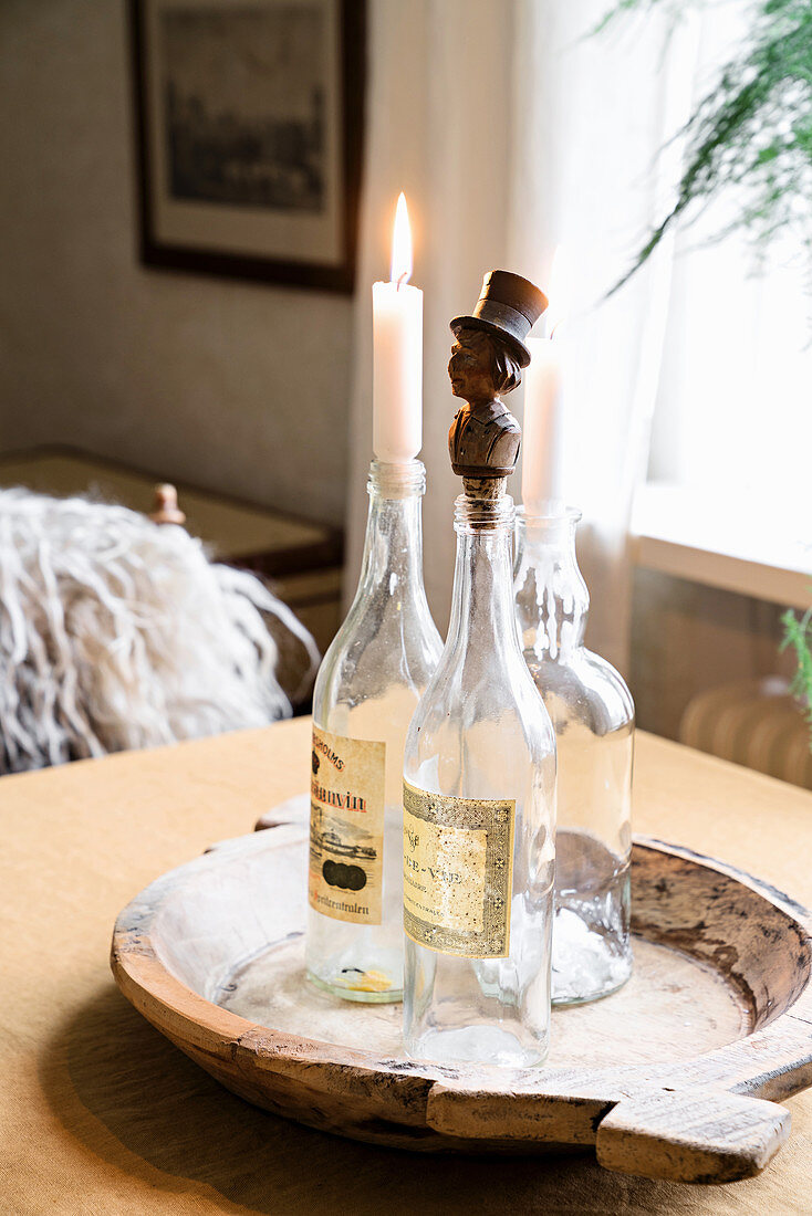 Stoppers and candles in vintage bottles on wooden tray