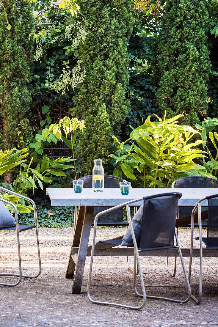 Stühle am Tisch auf der Terrasse im sommerlichen Garten