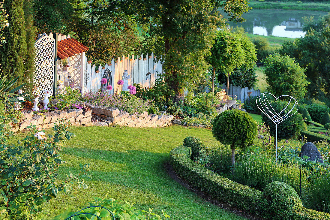 Garden on slop with box, limestone elements and ornaments