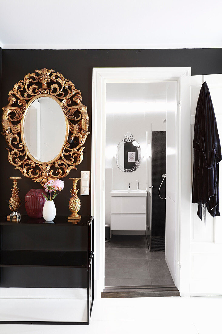 Oppulenter Spiegel mit geschnitztem Goldrahmen neben Tür zum Badezimmer