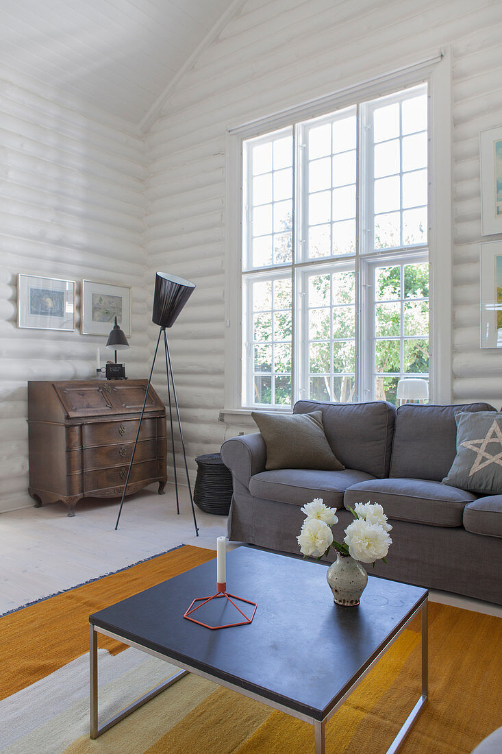 Coffee table, grey sofa, classic standard lamp and antique bureau in white-painted log cabin