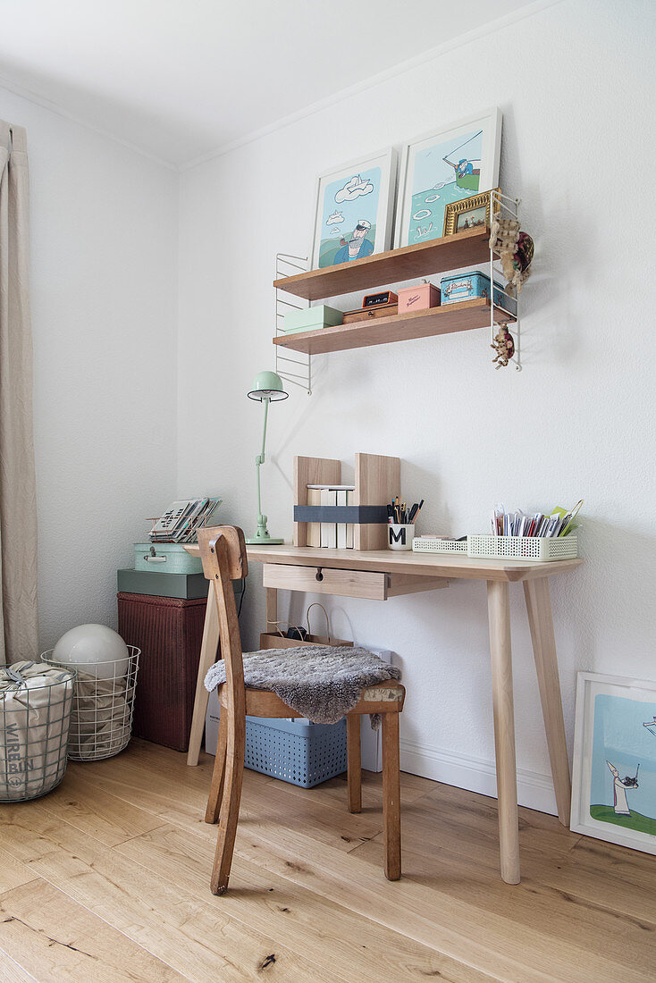 Narrow desk and pale wooden shelves in teenager's bedroom
