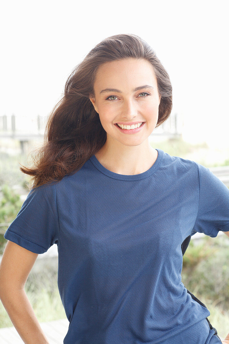 A young brunette woman wearing a short-sleeved blue t-shirt