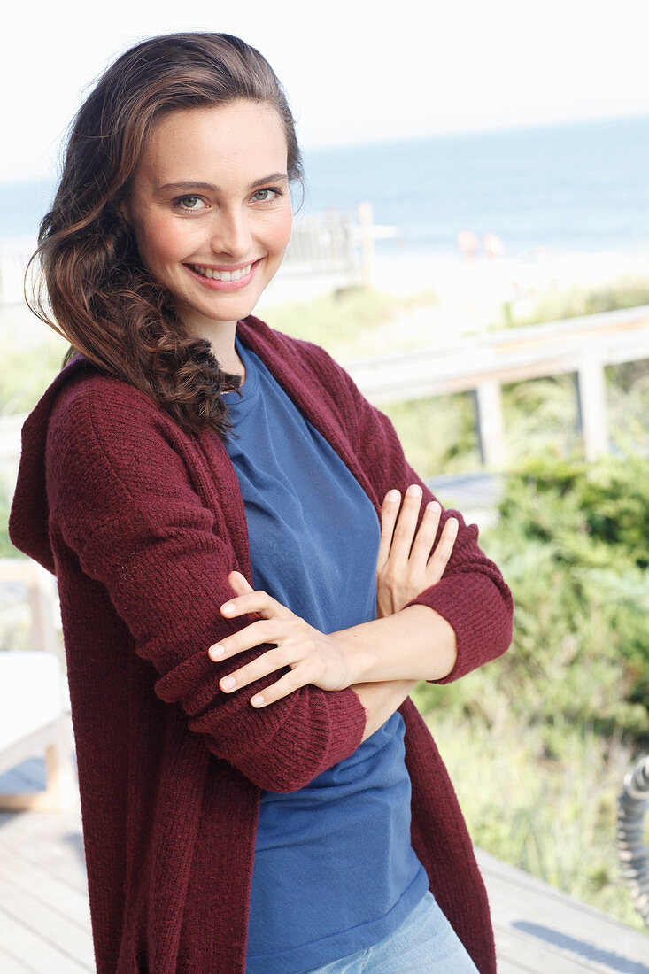 Junge brünette Frau in blauem Shirt und weinroter Strickjacke