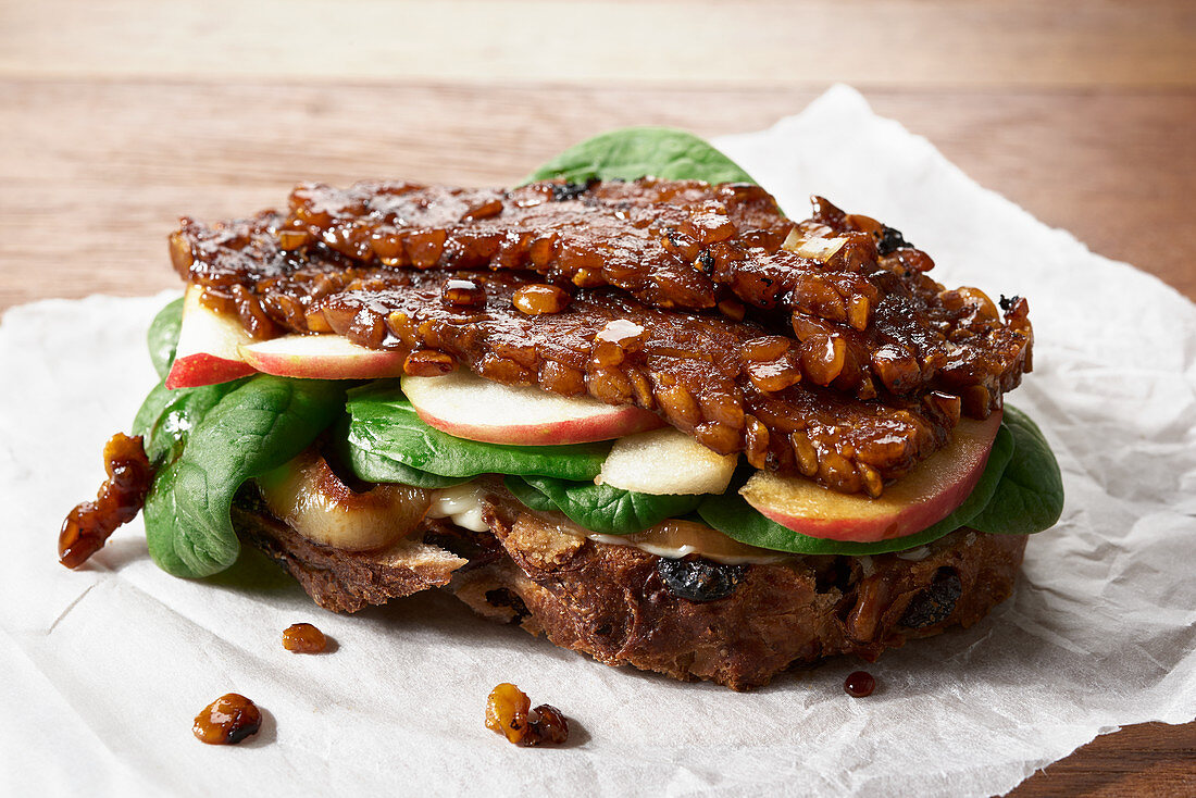 Marinated Lupini Bean Tempeh open-faced sandwich with sliced apple, spinach and grilled onions