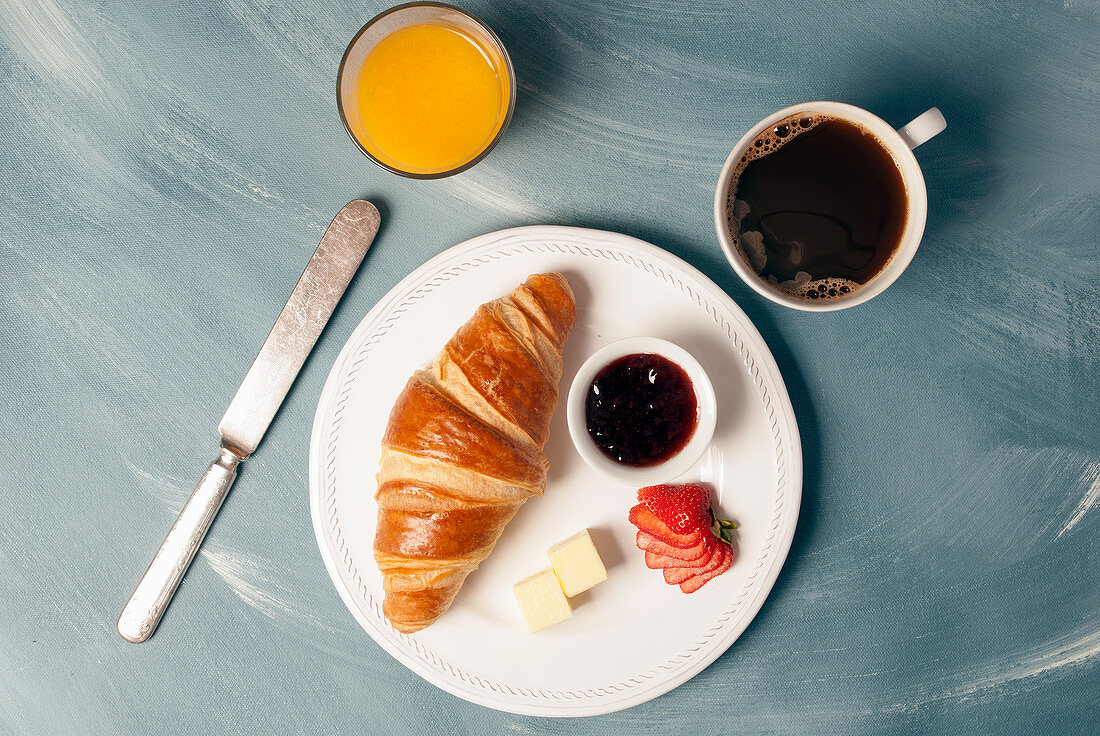 Klassisches kontinentales Frühstück mit Kaffee, Croissant und Marmelade