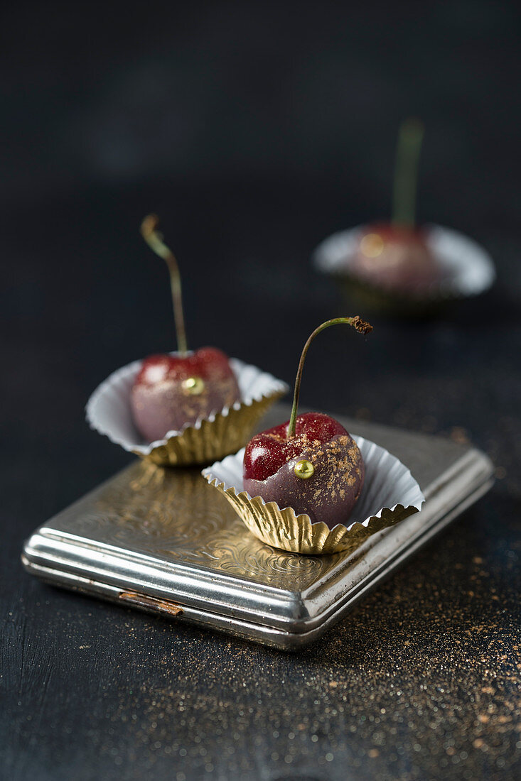 Kirschen mit gefärbter Schokolade und Goldglitzer