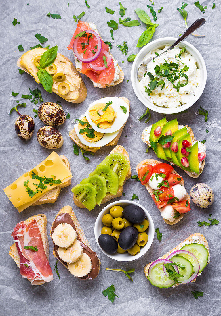 Assorted healthy ciabatta sandwiches with dips, fish, cheese, meat, vegetables, fruits