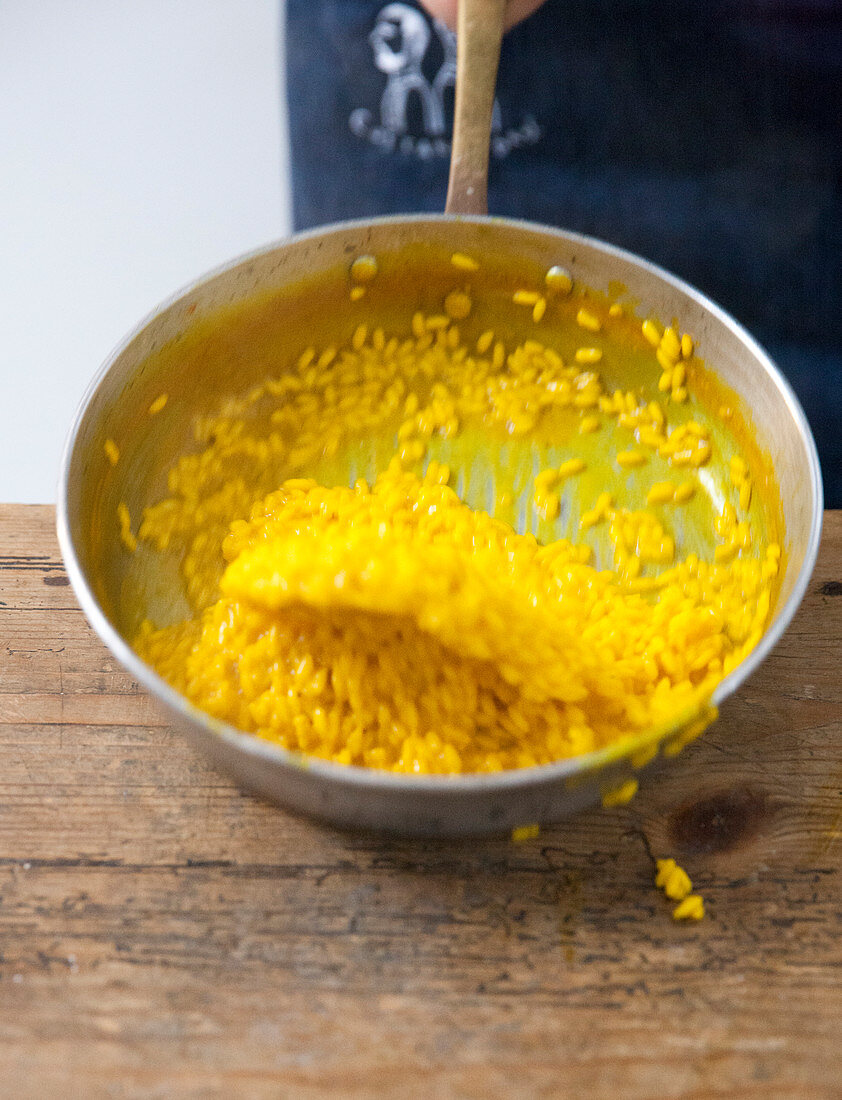 Safranrisotto mit Butter und Parmesan mischen