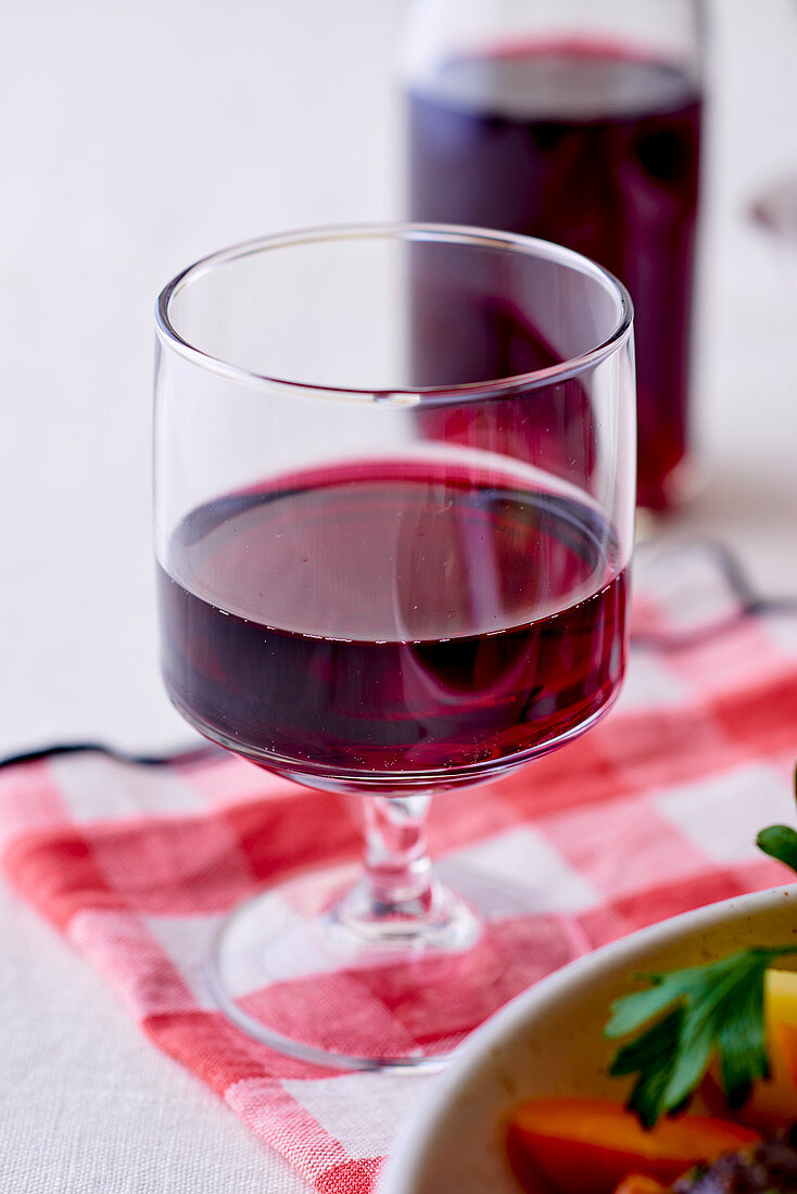 A glass of red wine on a checkered napkin