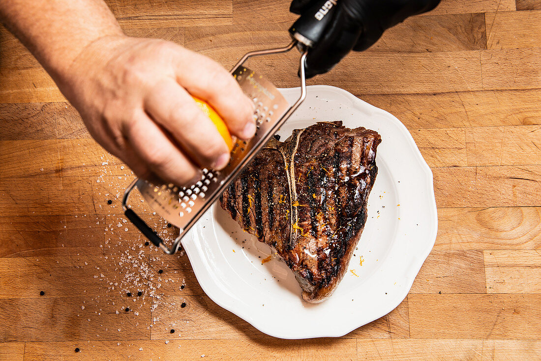 Sprinkling a porterhouse steak with orange zest