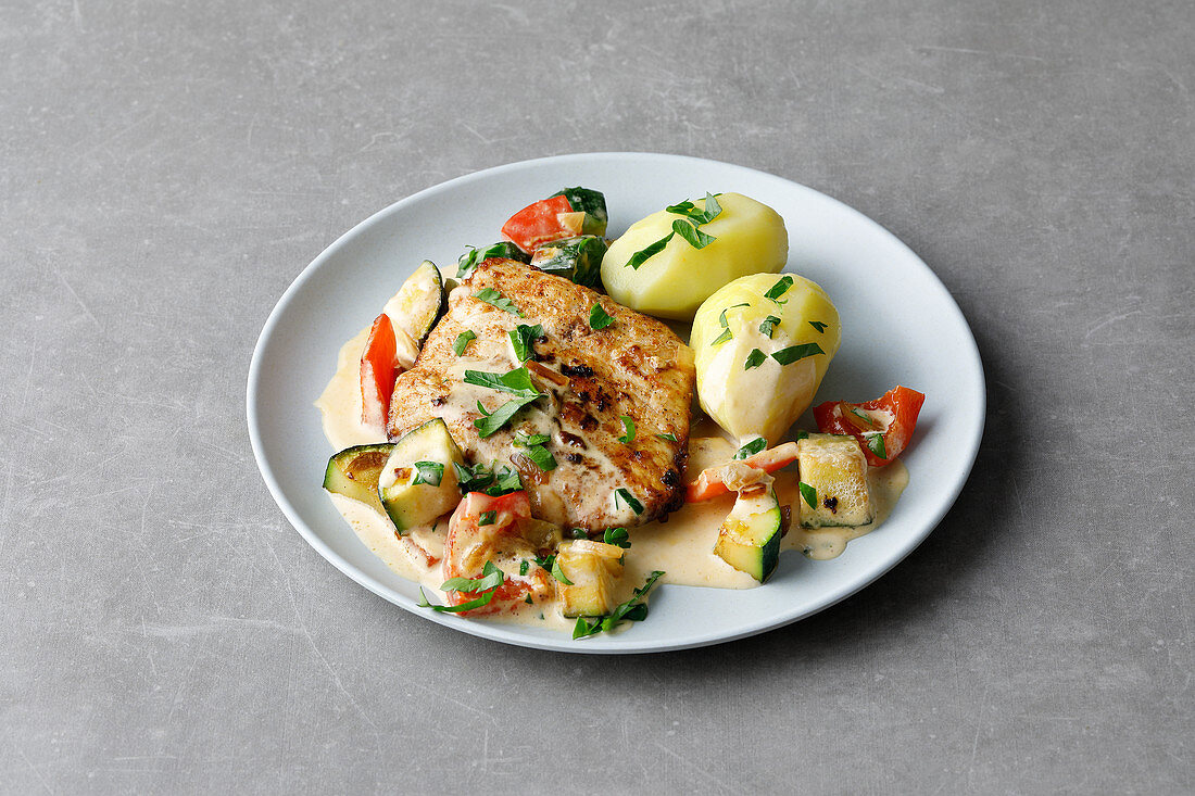 Pork schnitzel in a creamy sauce with a courgette medley and potatoes