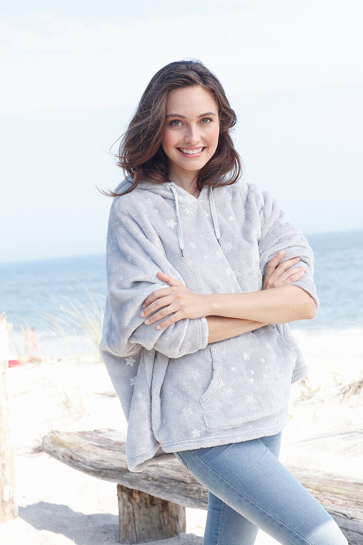 A young brunette woman wearing a light grey hoodie and jeans