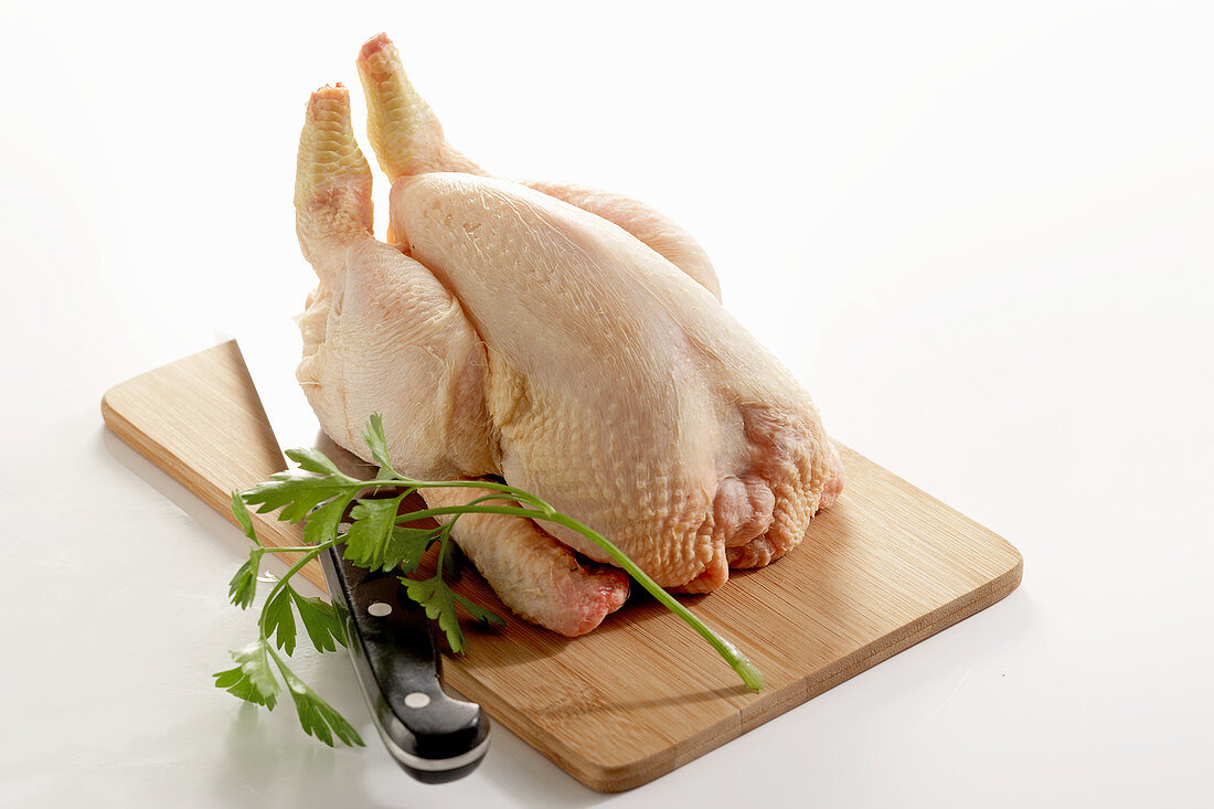 Whole raw poussin on a wooden board