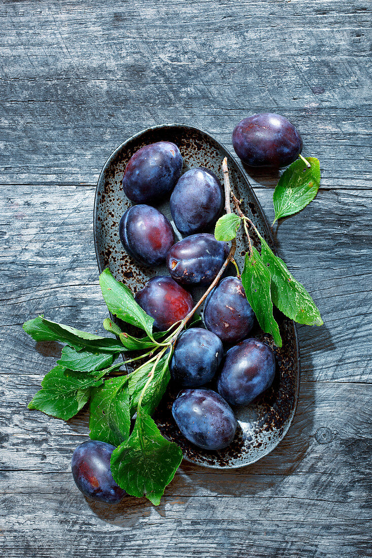 Plums with leaves in a bowl