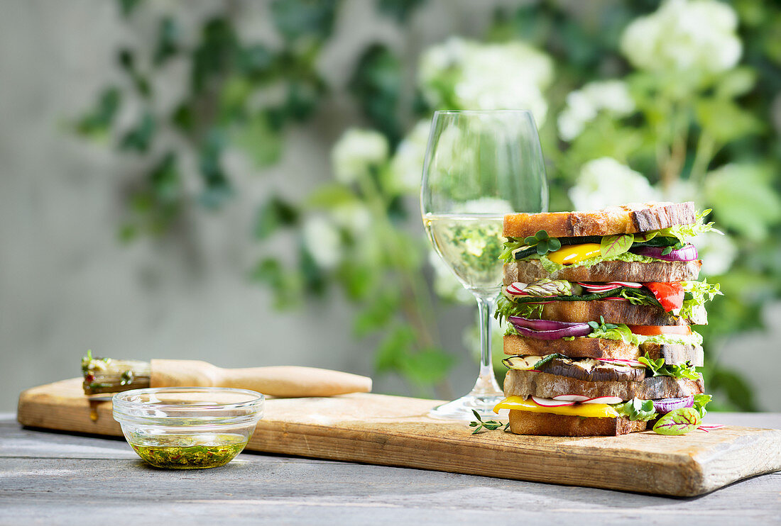 Gestapelte Sandwiches und Glas Weißwein