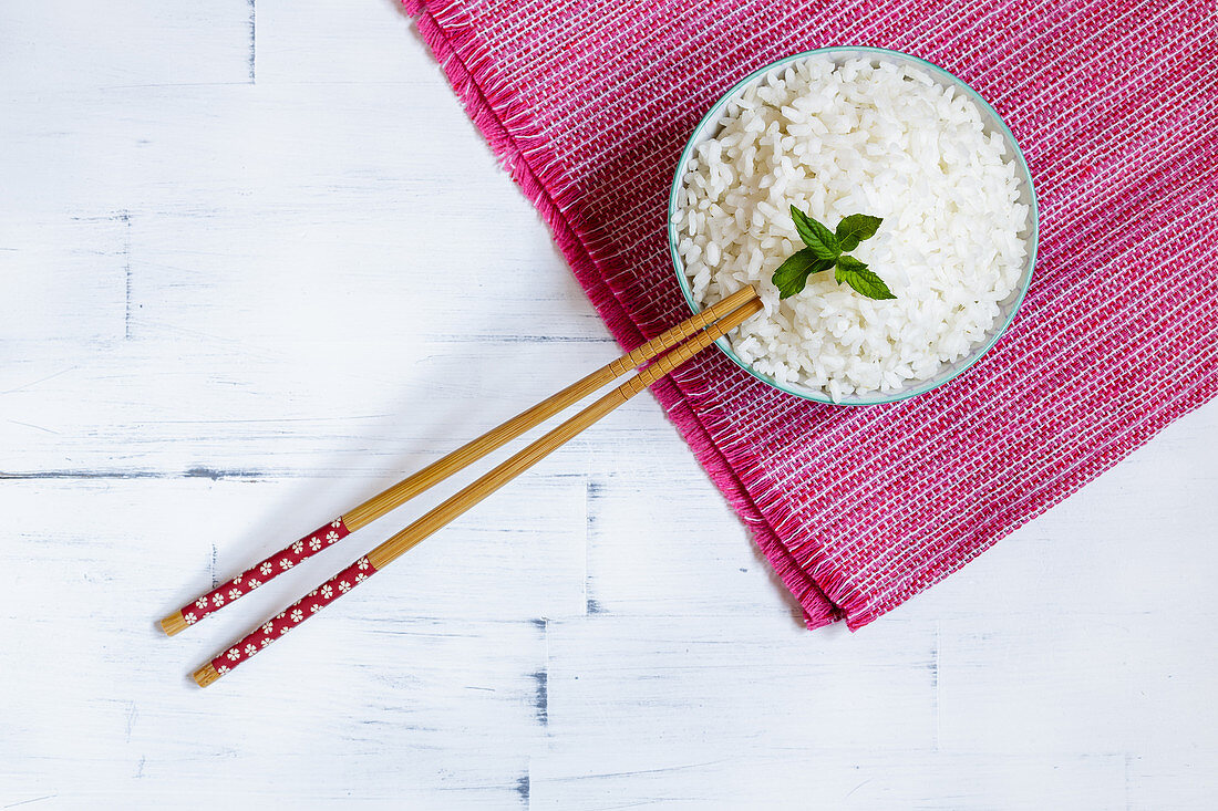 Boiled jasmine rice in a bowl with chopsticks