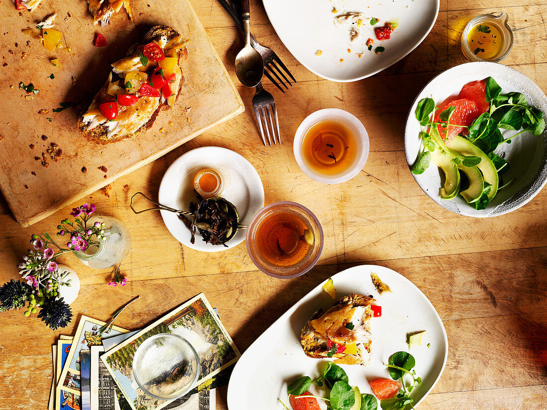 Tischszene mit halb gegessenen Brötchen, Salat und Gewürztee