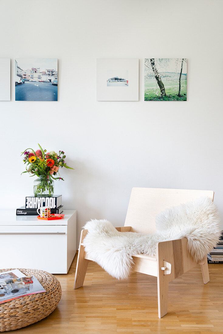 Armchair with fur rug and pouffe in front of low sideboard in living room