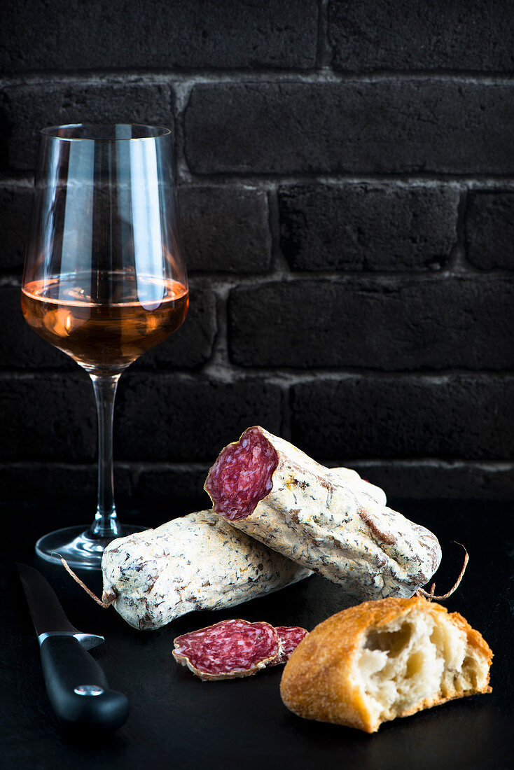 A glass of rose wine with salami and bread