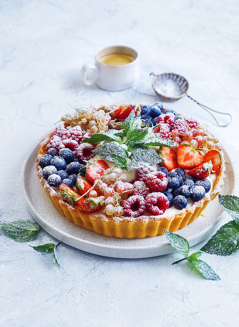 Berry tart with powdered sugar and fresh mint