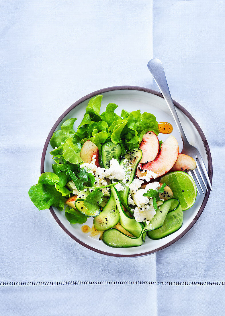 Salat mit Gurke, Pfirsichen, Feta und Limette