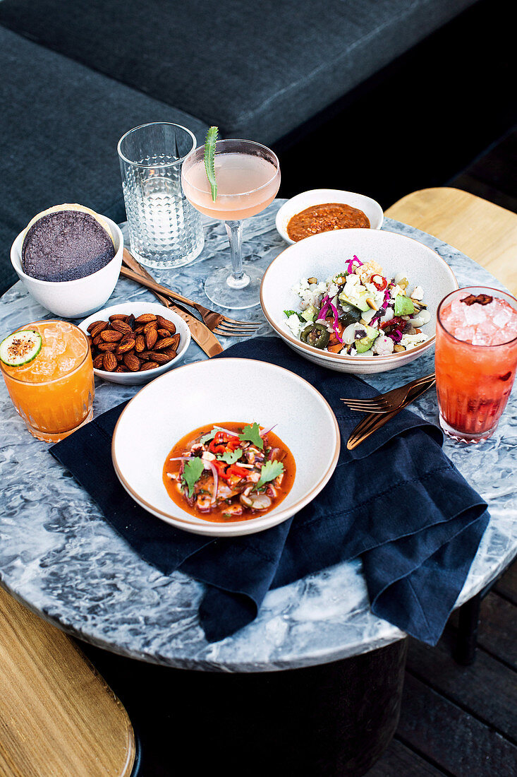 Seafood soup, feta salad, salted almonds and cocktails on restaurant table