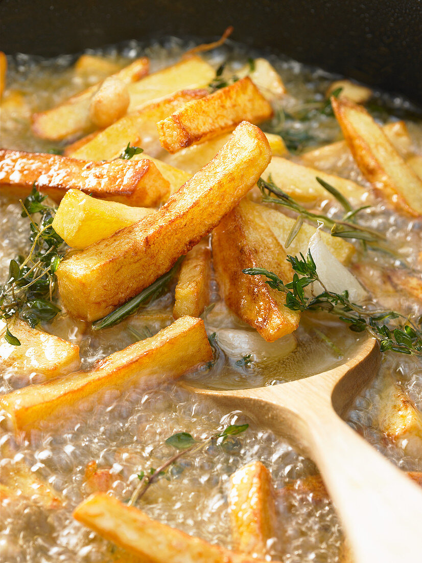 Tuscan fries with garlic, thyme and rosemary in frying oil
