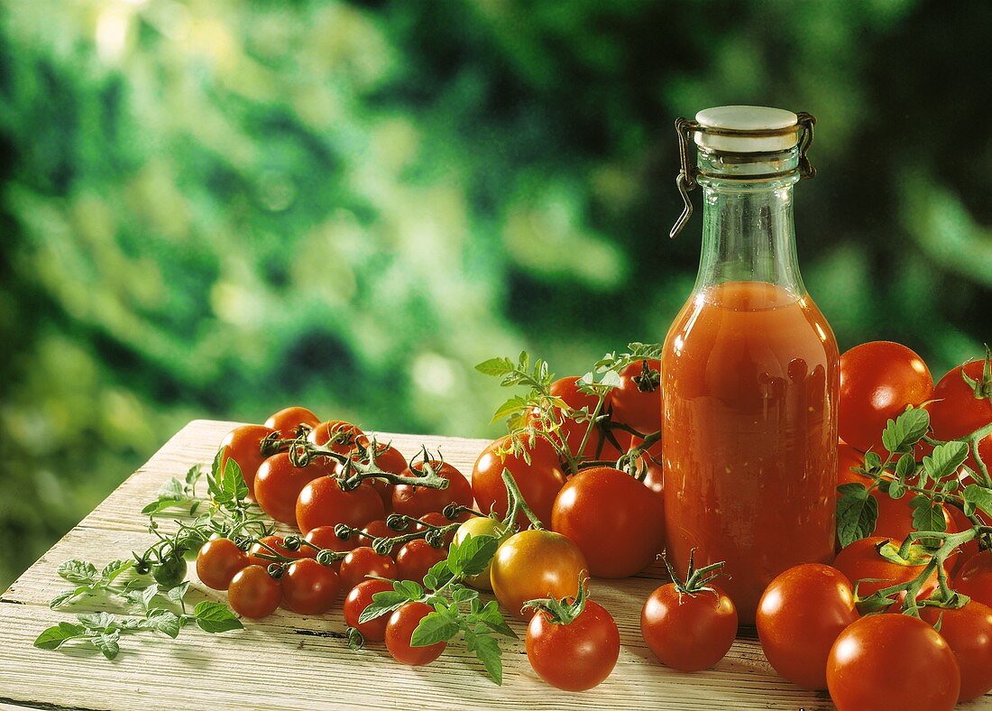 A bottle of tomato juice & fresh tomatoes on wooden table