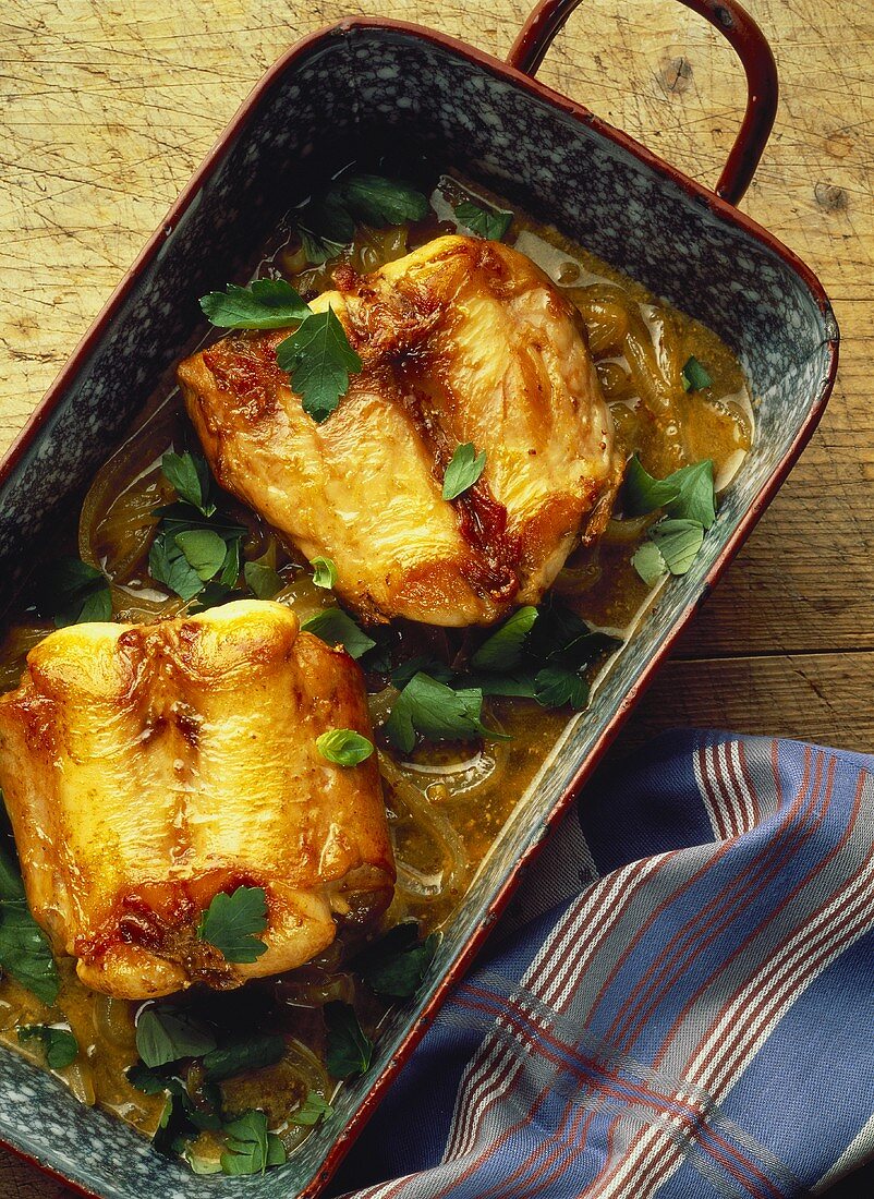 Braised rabbit with onions & parsley in roasting dish