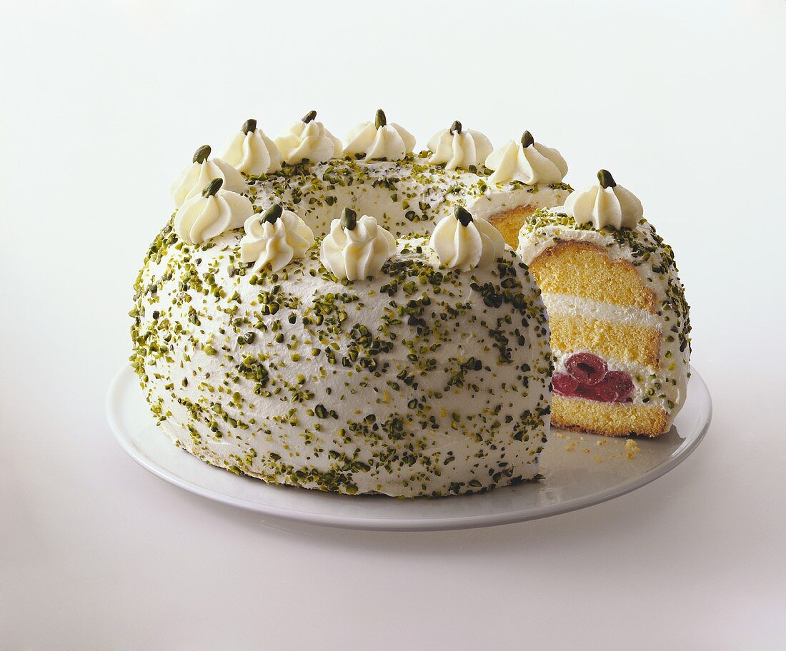 Crown cake with cream, cherries and chopped pistachios