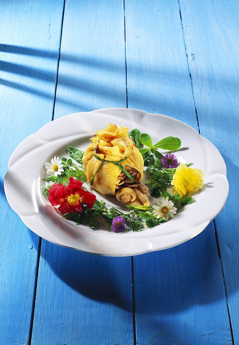 Crepessäckchen mit Champignonfüllung & Blütensalat auf Teller