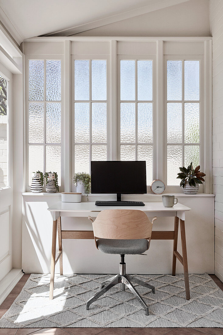 Computer on desk below lattice window with textured glass