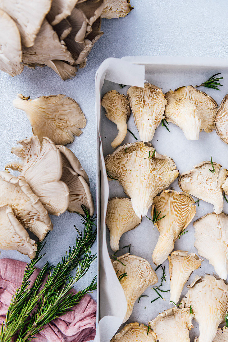 Oyster mushrooms with rosemary leaves on a baking sheet