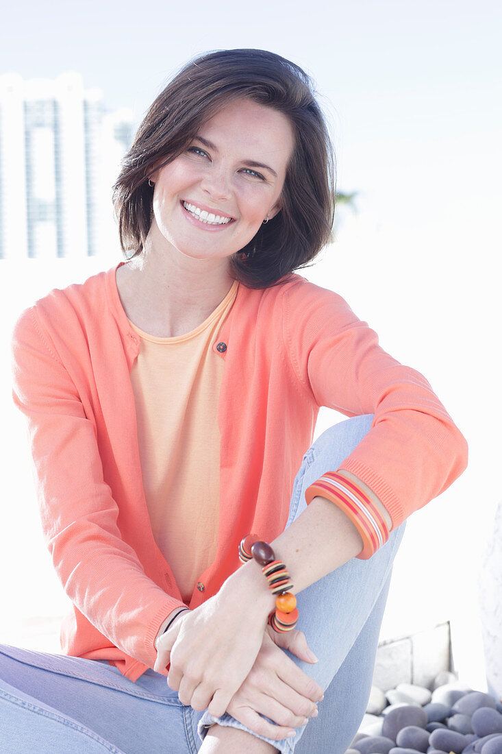 A young woman wearing an apricot top, cardigan and jeans