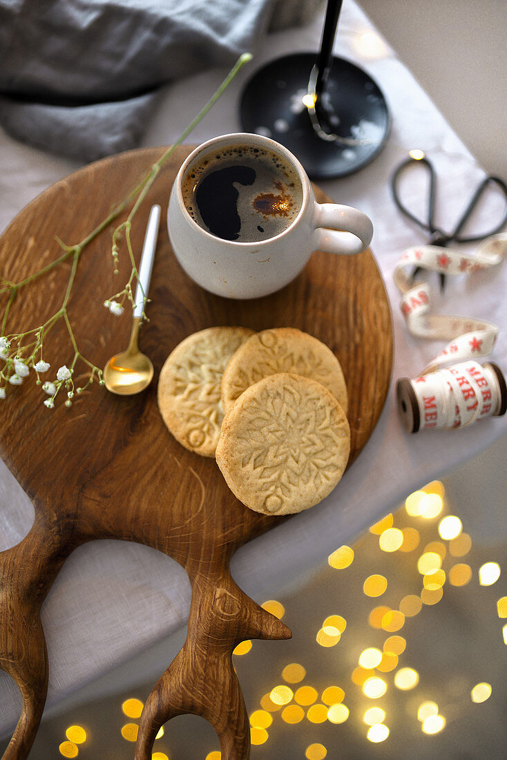 Eine Tasse Kaffee auf Holzbrett mit Keksen (weihnachtlich)