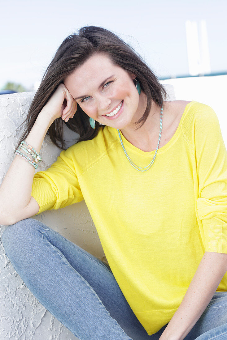A young woman wearing a long-sleeved yellow top and jeans