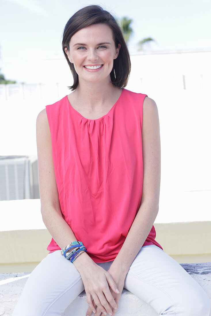 A young woman wearing a pink top and white white trousers