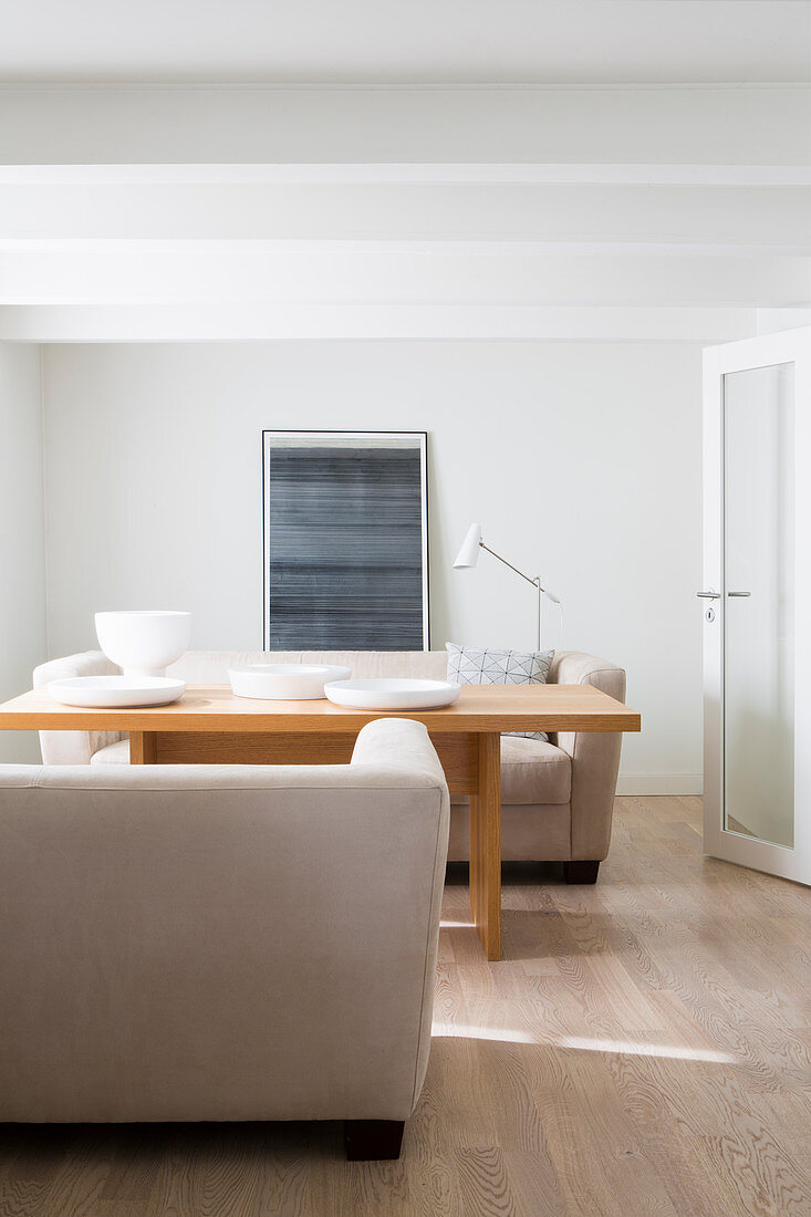 White bowls on wooden table between two sofas facing one another