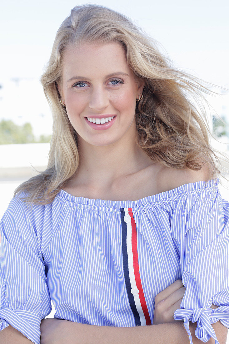 A young blonde woman wearing a blue-and-white striped Carmen blouse