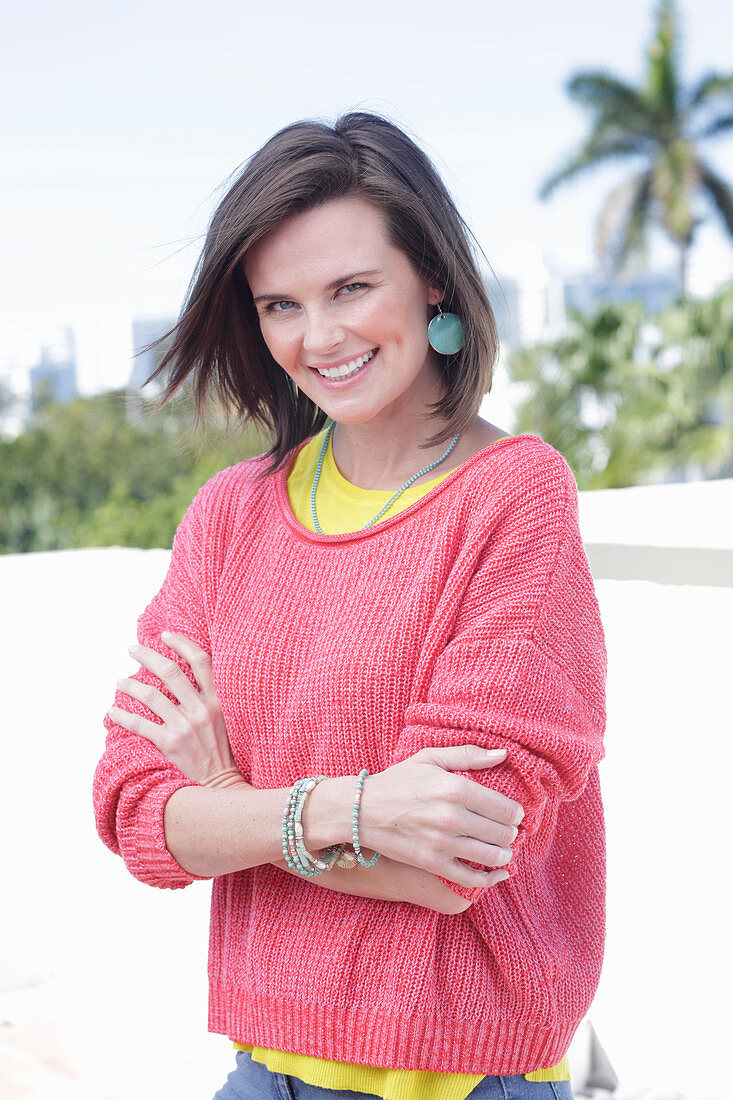 A young woman wearing large earrings, a fuchsia jumper and a yellow top