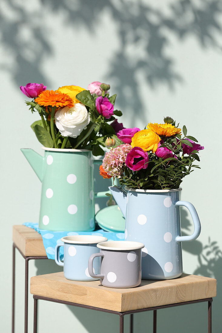 Gerbera daisies, ranunculus and anemones in pastel jugs with polka-dot patterns